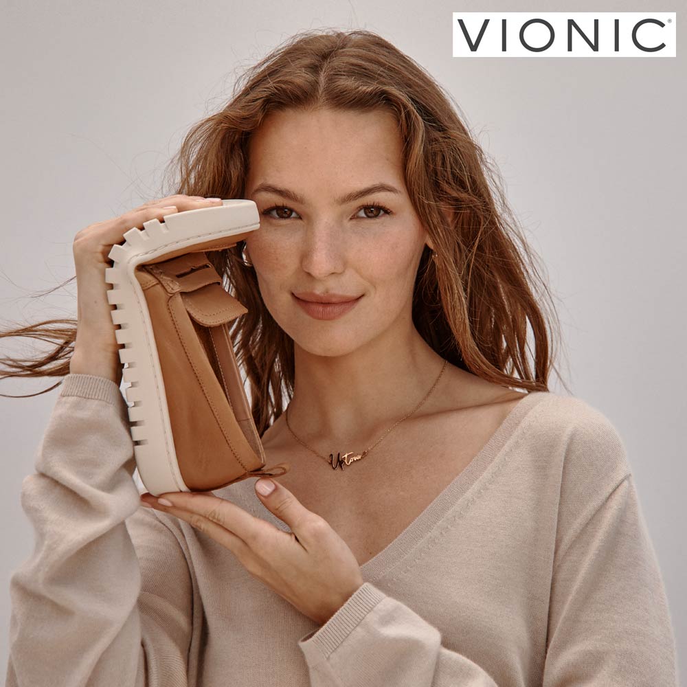 Woman holding a Vionic shoe against a plain background
