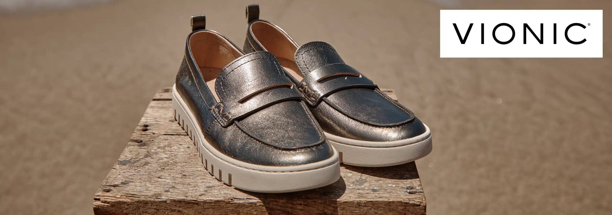 Pair of metallic loafers on a wooden block with 'Vionic' branding in the corner.
