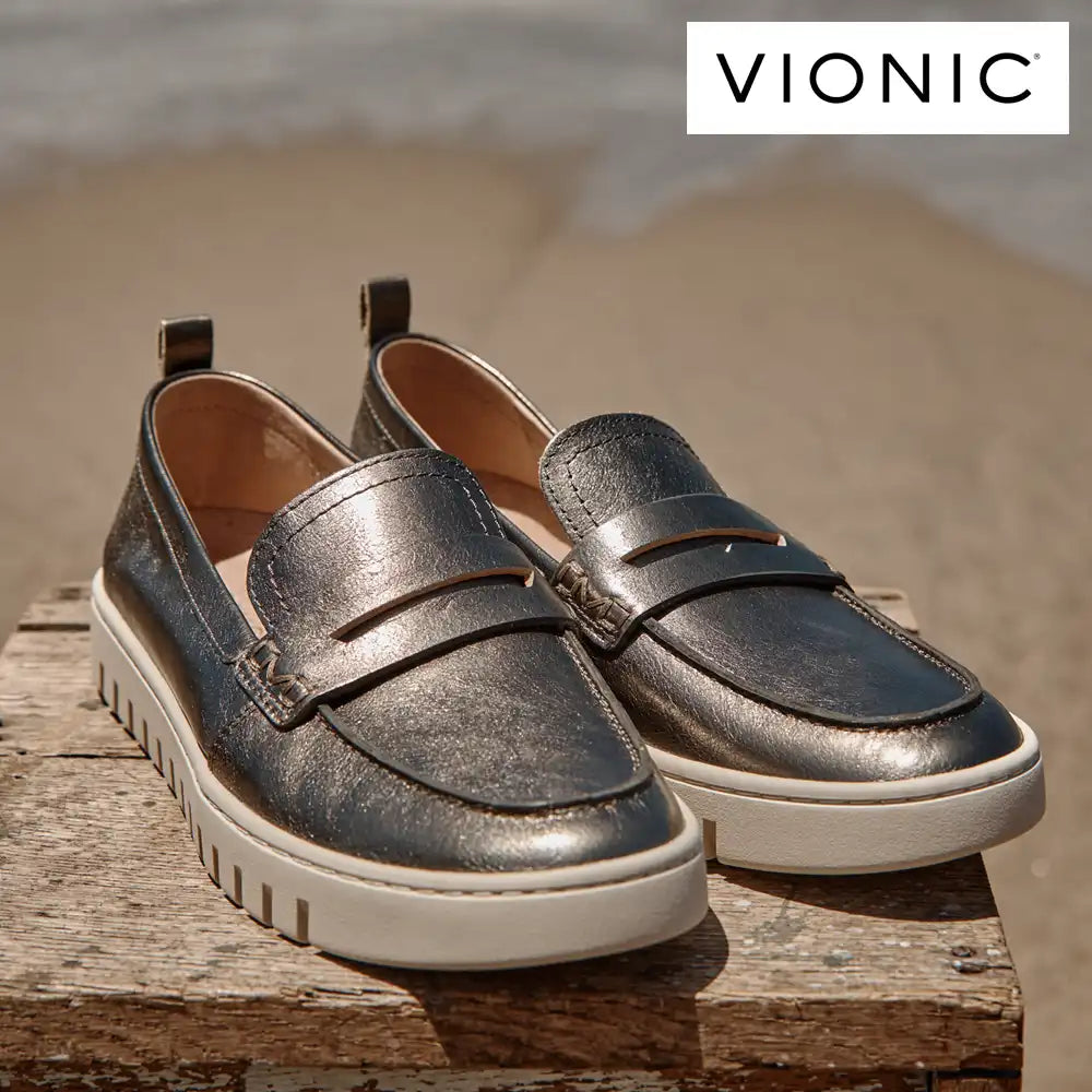 Pair of metallic loafers on a wooden surface with Vionic logo above.