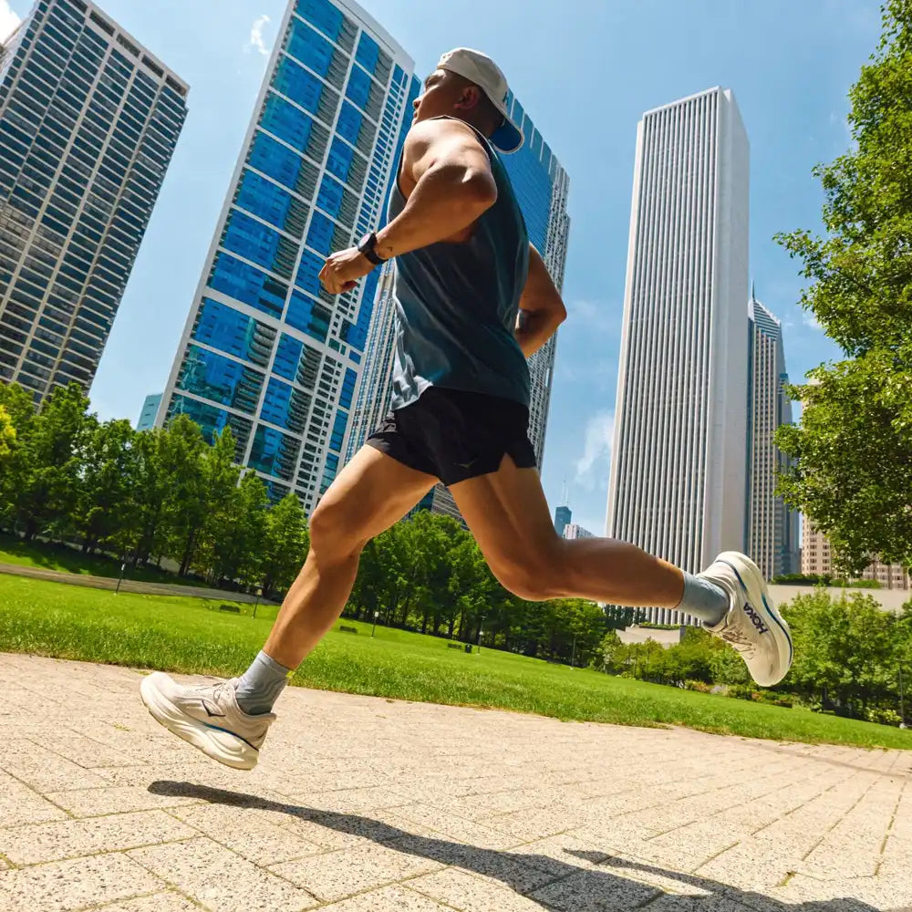 Person running on a path with city skyline and trees in the background